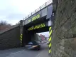 Car driving under low railway bridge with hi-vis markers