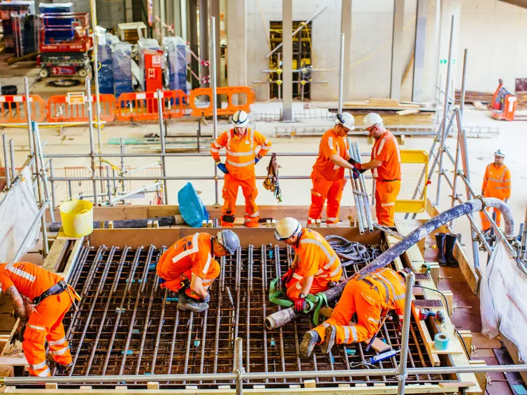 Men wearing hi-vis working inside railway station.