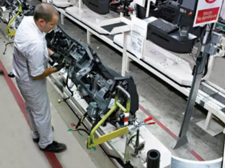 man working on car engine on a conveyor system.