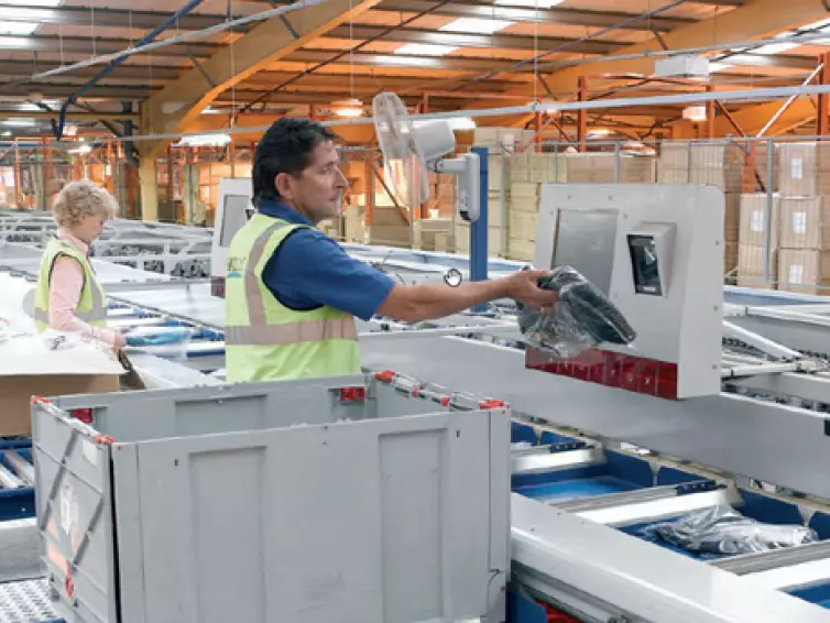 People packing clothes from a conveyor system.