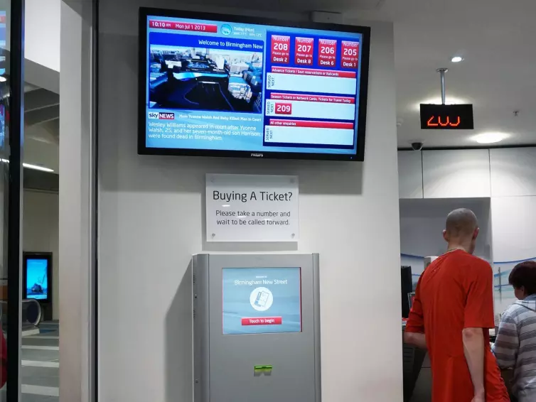 Information screen and ticketing machine in train station.