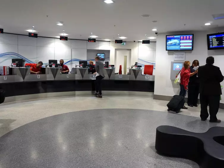 People viewing screens in rail ticket office.