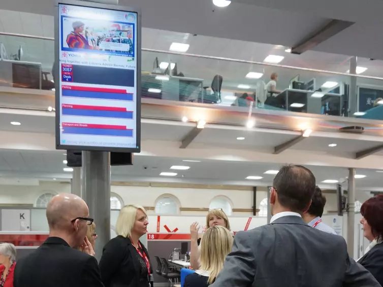 People underneath an information screen for tickets.