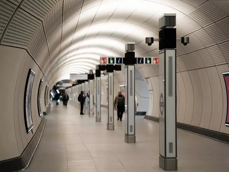 Elizabeth line underground station tunnel with signage to fire alarms and information.