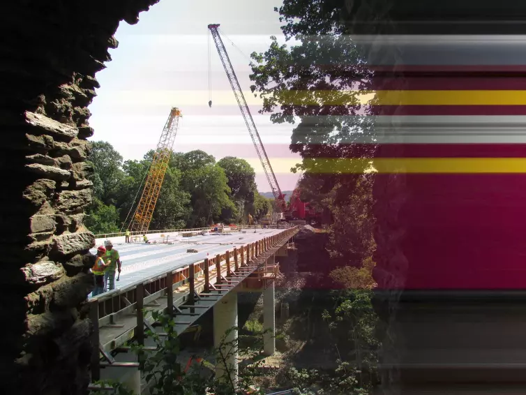 Workers on a bridge with cranes.