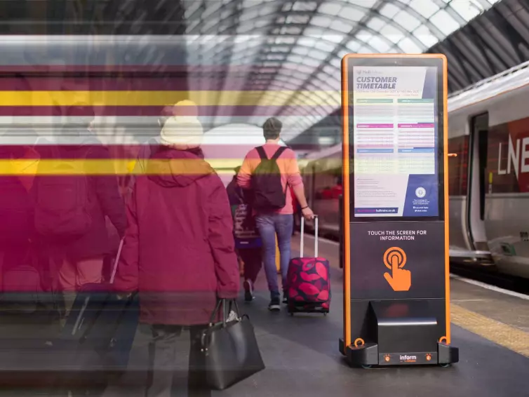 Information totem on Kings Cross station platform next to LNER train.