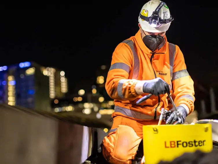 Man in hi-vis sat down, working on railway track.