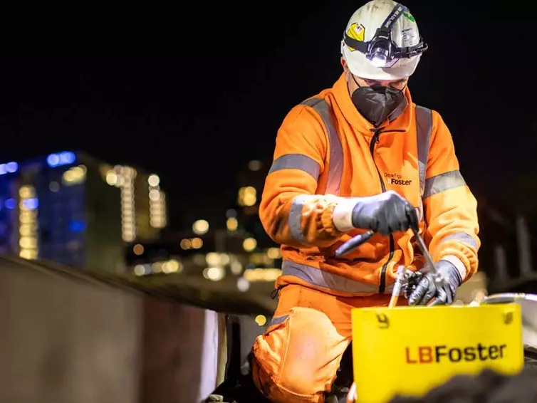 Man in hi-vis sat down, working on railway track.