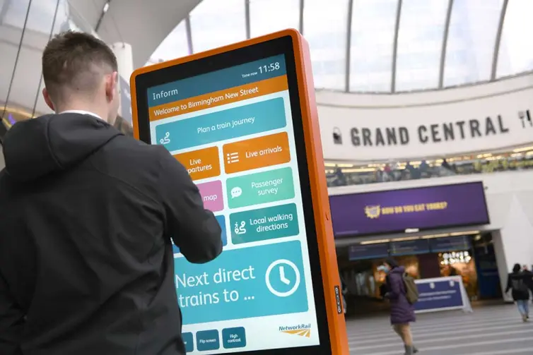 Man using touchscreen information totem in railway station.