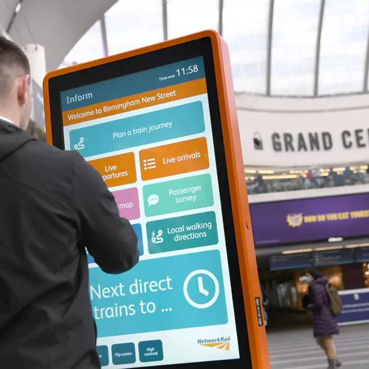 Man using touchscreen information totem in railway station.