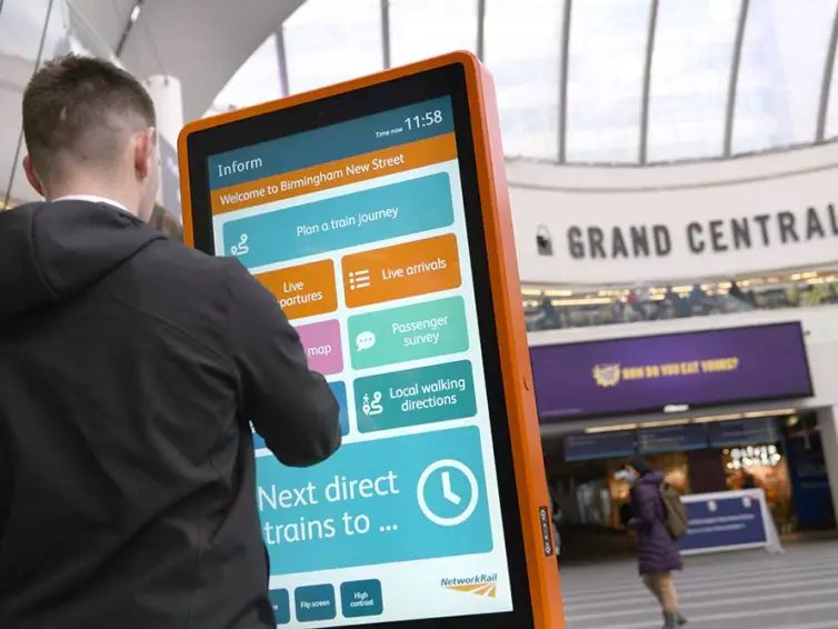 Man using touchscreen information totem in railway station.