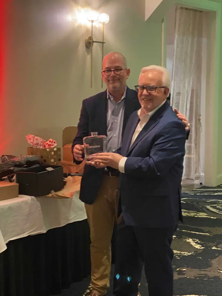 two men smiling in front of a gift table.