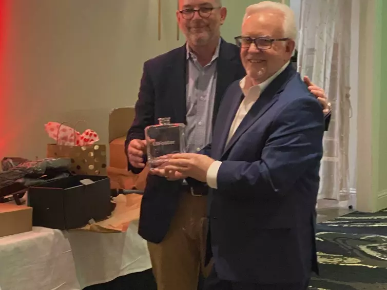 two men smiling in front of a gift table.