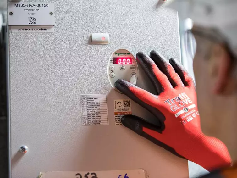 man inspecting electrical equipment in station.