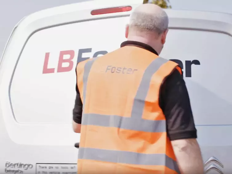 Man in hi-vis closing a LB Foster white van door.