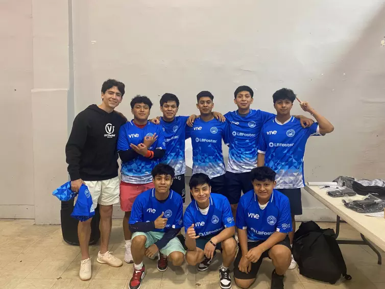 eight boys and their coach wearing blue L.B. Foster branded jerseys.