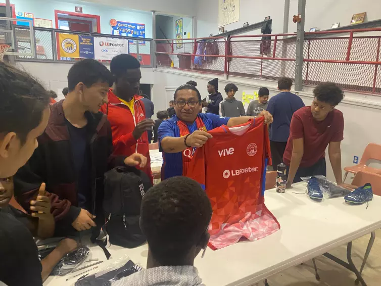 group of boys being given red L.B. Foster branded jerseys.