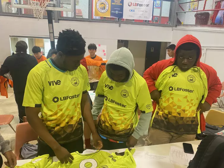 three boys trying on yellow L.B. Foster jerseys.