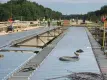 two rows of steel bridge decking placed on a bridge construction site with workers in the background