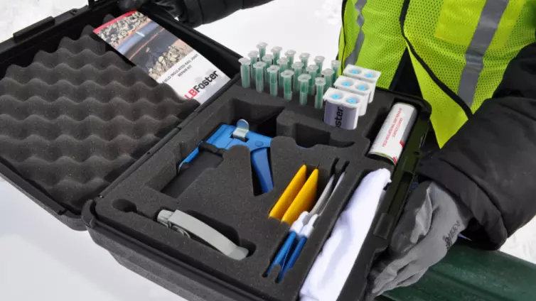 Opened box showing kit with surface cleaner, applicator gun, filler adhesive, sprayer with dipping tool, mixing nozzle, resealable dispensing bags, spreader, dusting brush, and cloth rags.