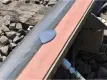 A close-up view of a railroad track where a puddle of purple-grey liquid is shown on an orange foam  bar attached to the rail