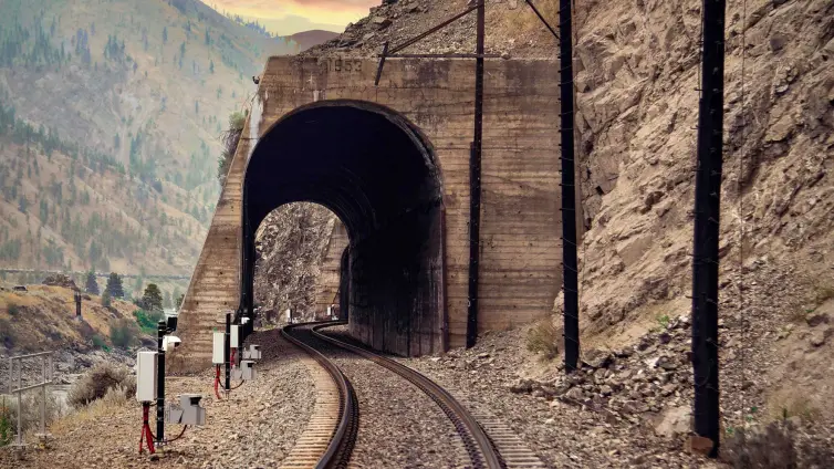 rockfall LiDAR installed next to a railroad track running through a tunnel in a mountainside.