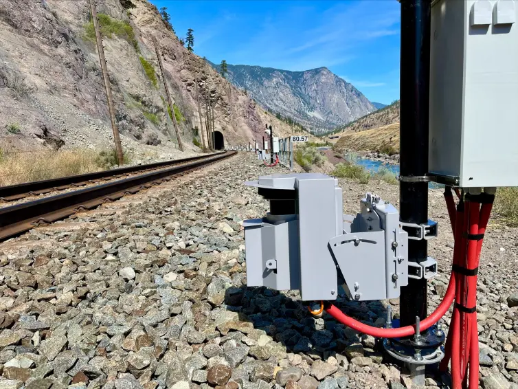 rockfall LiDAR installed next to a railroad track running through a tunnel in a mountainside.