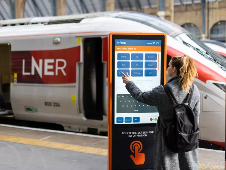 A woman is positioned next to a train, emphasizing her connection to travel and movement.