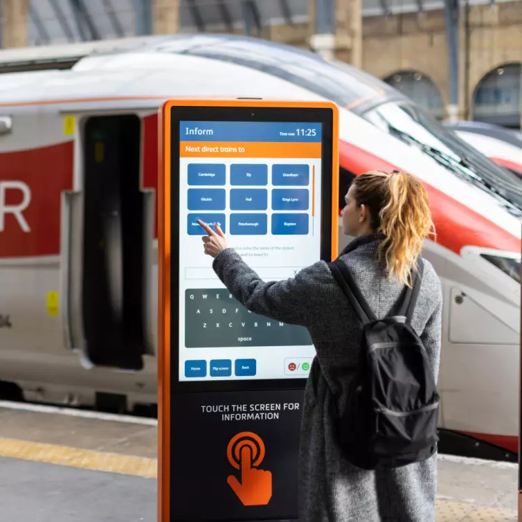 A woman is positioned next to a train, emphasizing her connection to travel and movement.