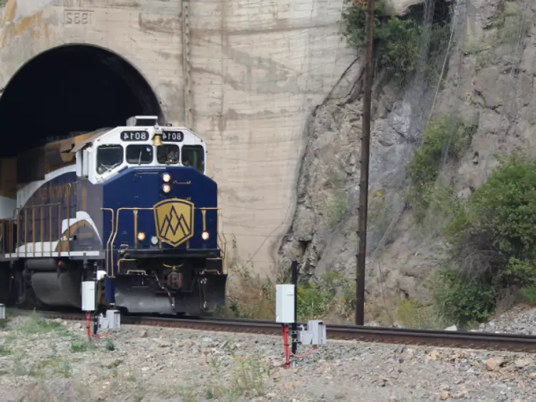 A train travels through a dark tunnel, showcasing the contrast between the illuminated train and the shadowy passage.