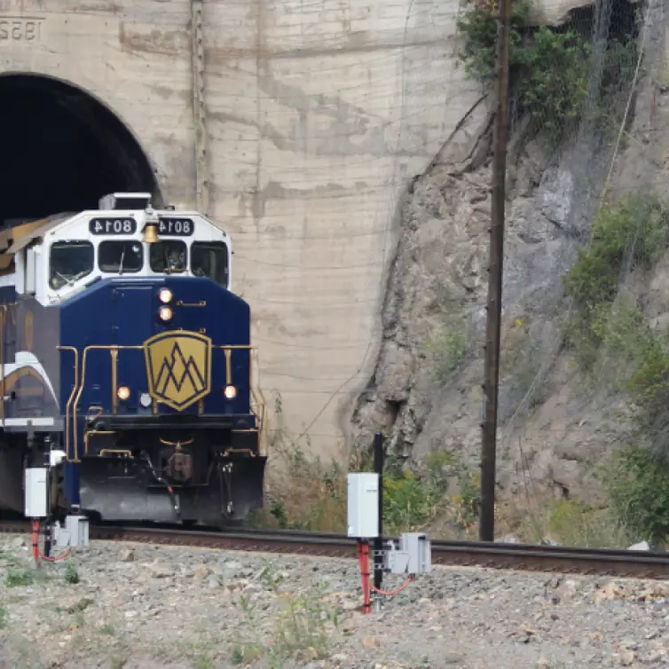 A train travels through a dark tunnel, showcasing the contrast between the illuminated train and the shadowy passage.