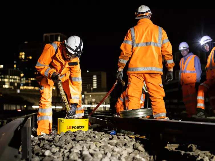 Workers in hi-vis equipment working on railway track.