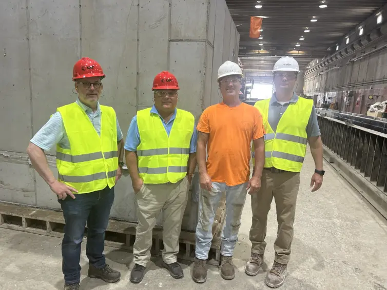 Four men smiling wearing high-vis vests, hard hats, and safety glasses.